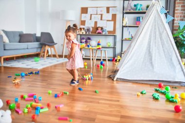 Genç, güzel çocuk anaokulunda tahta tren oyuncağıyla oynuyor.