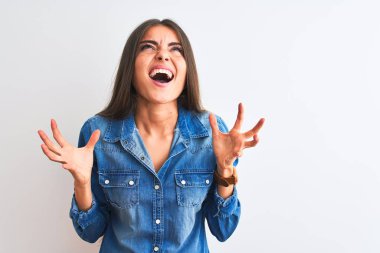 İzole edilmiş beyaz arka plan üzerinde duran sıradan bir kot giyen genç ve güzel bir kadın çılgın ve sinirli bir şekilde bağırıyor ve agresif bir ifade ve kollarla bağırıyor. Hayal kırıklığı konsepti.