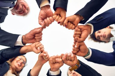 Group of business workers smiling happy and confident. Standing on a circle with smile on face doing symbol with fists together at the office.