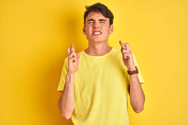 Teenager Boy Wearing Yellow Shirt Isolated Background Gesturing Finger Crossed — Stock Photo, Image