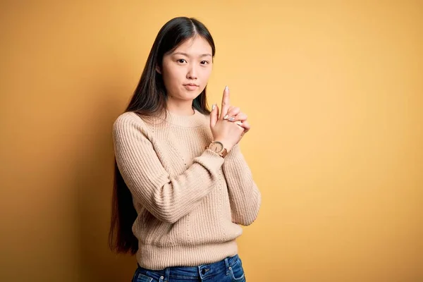 年轻美丽的亚洲女人 身穿休闲装 披着黄色孤立的背景 手拿着象征性的枪 玩着猎枪 满脸怒容 — 图库照片