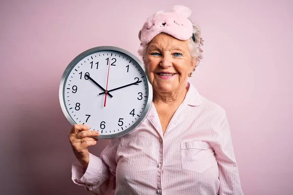 Senior Beautiful Woman Wearing Sleep Mask Holding Big Clock Isolated — Stok fotoğraf