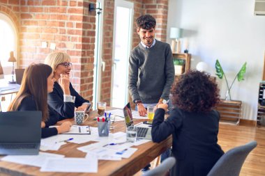 Bir grup iş adamı mutlu ve kendinden emin gülümsüyor. Yüzünde gülümsemeyle birlikte çalışmak. Genç yakışıklı adam büroda belgeleri açıklıyor.