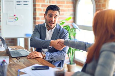 Mutlu ve kendinden emin gülümseyen genç ve güzel iş adamları. Ofiste anlaşmak için gülümseyerek tokalaşmak.