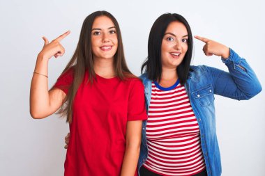 Young beautiful women wearing casual clothes standing over isolated white background smiling pointing to head with both hands finger, great idea or thought, good memory