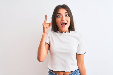 Genç güzel kadın izole beyaz arka plan üzerinde ayakta rahat t-shirt giyen başarılı bir fikir ile parmak yukarı işaret. Çıkıldı ve mutlu. Bir numara.