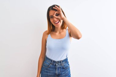 Beautiful redhead woman standing over isolated background doing ok gesture with hand smiling, eye looking through fingers with happy face.