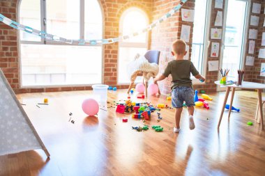 Anaokulunda pembe balonla oynayan beyaz bir çocuk. Anaokulu çocuğu oyuncaklarla oyun odasında mutlu.