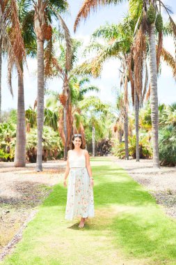 Güneşli bir yaz gününde yeşil parkta mutlu ve neşeli gülümseyen güzel bir kadın.