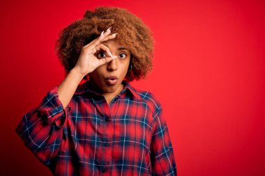 Kıvırcık saçlı, normal bir jest yapan, şaşırmış yüzüyle, parmaklarından bakan güzel Afro-Amerikan kadın. İnançsız ifade.