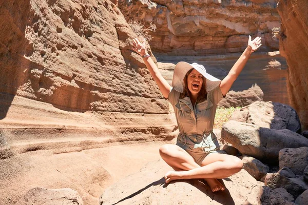 Young beauitufl hiker woman trekking natural orange mountain with arms raised celebrating summer holidays