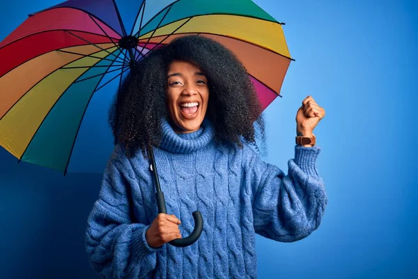 冬の天候の雨のためのカラフルな傘の下でアフロの髪を持つ若いアフリカ系アメリカ人女性は誇りと勝利と成功を祝う叫び非常に興奮し 感情を応援 — ストック写真