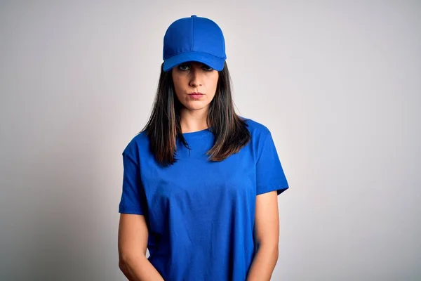 Young delivery woman with blue eyes wearing cap standing over blue background skeptic and nervous, frowning upset because of problem. Negative person.