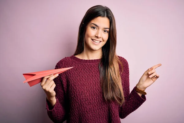 Menina Bonita Jovem Segurando Avião Papel Sobre Fundo Rosa Isolado — Fotografia de Stock