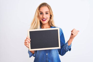 Genç, güzel bir öğretmen kadın elinde tahtayla izole edilmiş beyaz arka planda duruyor ve gülümseyen bir gülümsemeyle baş parmağıyla işaret ediyor.