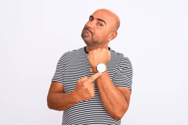 Middle age handsome man wearing striped navy t-shirt over isolated white background In hurry pointing to watch time, impatience, looking at the camera with relaxed expression