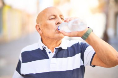 Kıdemli yakışıklı adam mutlu ve kendinden emin gülümsüyor. Kasaba caddesinde dikilmiş su içiyorum.