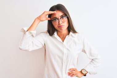 Young beautiful businesswoman wearing glasses standing over isolated white background worried and stressed about a problem with hand on forehead, nervous and anxious for crisis