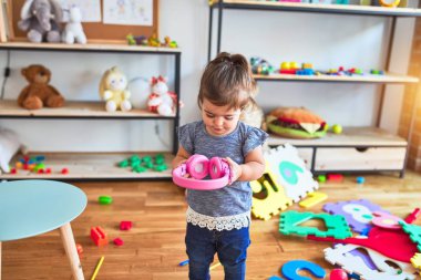 Beautiful toddler holding headphones standing at kindergarten