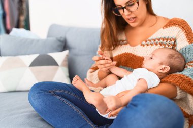 Genç, güzel bir kadın ve bebeği evdeki kanepede. Yeni doğan anne rahatlıyor ve dinleniyor.
