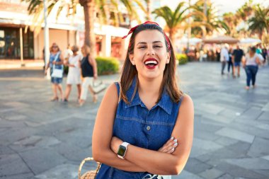 Genç, güzel bir kadın mutlu bir şekilde gülümsüyor. Güneşli bir yaz gününde Tenerife, Puerto de la Cruz sokaklarında yürüyor.
