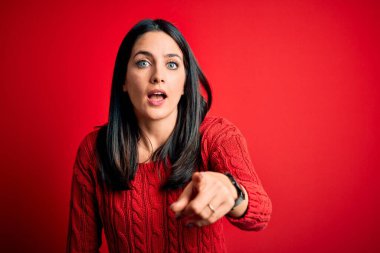 Young brunette woman with blue eyes wearing casual sweater over isolated red background pointing displeased and frustrated to the camera, angry and furious with you