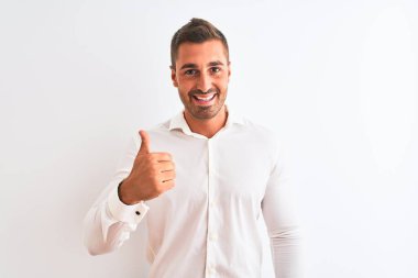 Young handsome business man wearing elegant shirt over isolated background doing happy thumbs up gesture with hand. Approving expression looking at the camera showing success.