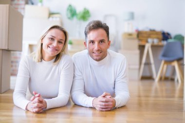 Karton kutuların etrafındaki yeni evde yere uzanmış genç ve güzel bir çift.