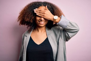 Afro saçlı, zarif ceketli, gülümseyen ve gülen elleri yüzlü, şaşırtmak için gözlerini kapatan Afro Amerikalı genç bir iş kadını. Kör kavram.