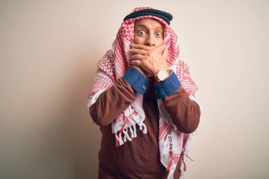 Tecrit edilmiş beyaz arka planda duran keffiyeh giyen kıdemli yakışıklı Arap adam yanlışlıkla ağızlarını kapatarak şok geçirdi. Gizli konsept.