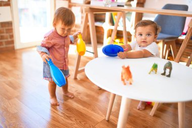 Anaokulunda bir sürü oyuncakla oynayan sevimli çocuklar.