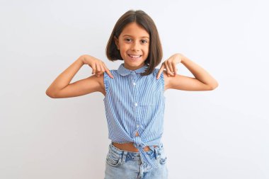 Genç, güzel bir kız çocuğu, mavi bir gömlek giyiyor, izole edilmiş beyaz arka plan üzerinde duruyor, kendine güvenen, yüzünde bir gülümsemeyle, kendini gururlu ve mutlu bir şekilde gösteriyor..