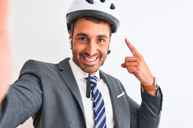 Young handsome business man wearing bike helmet taking a selfie over isolated background very happy pointing with hand and finger