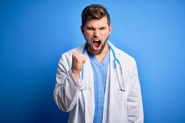 Sakallı, mavi gözlü, beyaz önlüklü, steteskop takmış kızgın, kızgın ve öfkeli genç bir doktor öfkeyle bağırırken yumruğunu kaldırıyor. Öfke ve agresif kavram.