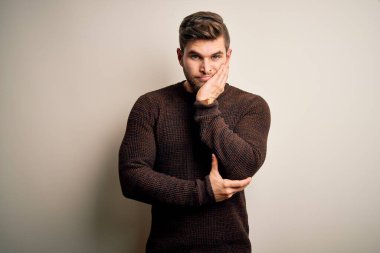 Young handsome blond man with beard and blue eyes wearing casual sweater standing thinking looking tired and bored with depression problems with crossed arms.