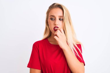 İzole edilmiş beyaz arka plan üzerinde kırmızı tişört giyen genç ve güzel bir kadın elleri ağız yiyen tırnaklarla gergin ve stresli görünüyor. Endişe sorunu.