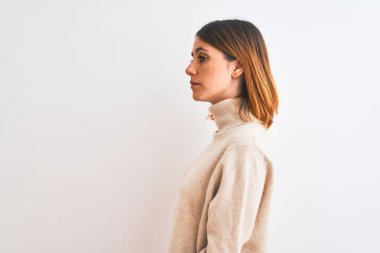 Beautiful redhead woman wearing winter turtleneck sweater over isolated background looking to side, relax profile pose with natural face with confident smile.