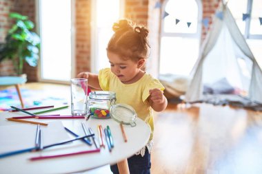 Anaokulunun masasında çikolata renkli toplarla oynayan güzel çocuk.