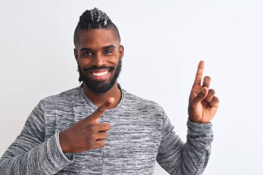 African american man with braids wearing grey sweater over isolated white background smiling and looking at the camera pointing with two hands and fingers to the side.