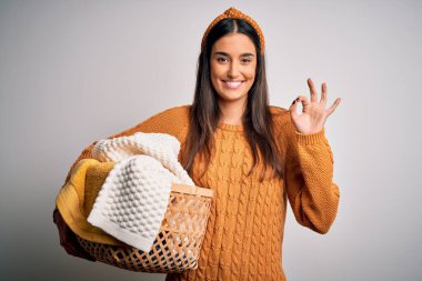 Genç, güzel esmer kadın ev işi yapıyor hasır sepeti ve giysileri tutuyor. İşaretleri parmaklarıyla yapıyor. Mükemmel bir sembol.
