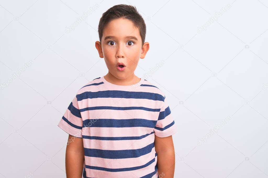 Beautiful kid boy wearing casual striped t-shirt standing over isolated white background afraid and shocked with surprise expression, fear and excited face.