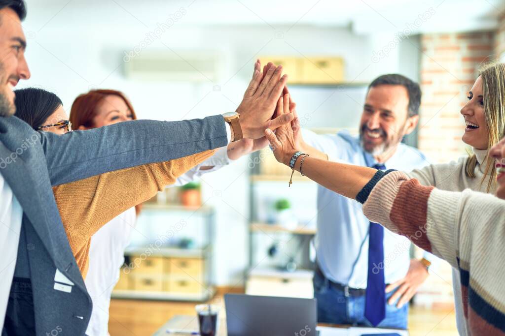 Group of business workers standing with hands together highing five at the office