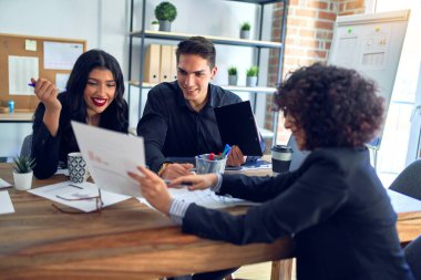Group of business workers smiling happy and confident. Working together with smile on face reading documents and  speaking at the office