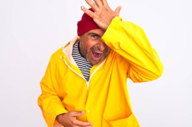 Yağmurluk giyen ve yünlü şapka takan orta yaşlı bir adam izole edilmiş beyaz arka planda duruyor. Hatayla el ele tutuşurken şaşırmış. Hatayı hatırla. Unuttum, kötü hafıza konsepti.