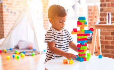 Güzel çocuk anaokulunda inşaat bloklarıyla oynuyor.