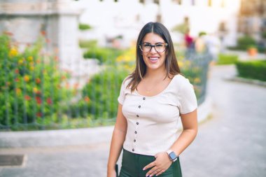 Mutlu ve kendinden emin gülümseyen genç ve güzel bir kadın. Kasaba caddesinde yüzünde gülümsemeyle dikilirken