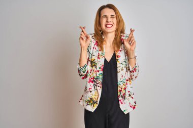 İzole bir arka plan üzerine bahar çiçeği ceketi giyen Kafkasyalı genç bir iş kadını umut ve gözler kapalı bir şekilde gülümseyerek işaret ediyor. Şans ve batıl inanç..