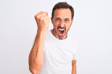 Orta yaşlı yakışıklı bir adam, izole edilmiş beyaz arka plan üzerinde dikilmiş kızgın ve kızgın sinirli sinirli bir şekilde yumruğunu kaldırırken öfkeyle bağırıyor. Öfke ve agresif kavram.