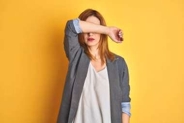 Kızıl saçlı beyaz iş kadını sarı arka planda. Tavşan kulaklı hareketler yapıyor. Avuçlarında alaycı ve şüpheci bakışlar var. Paskalya tavşanı kavramı.