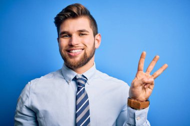 Sakallı, mavi gözlü, şık gömlekli ve kravatlı genç sarışın işadamı üç numaralı parmaklarıyla ayakta duruyor ve gülümsüyor, kendinden emin ve mutlu..
